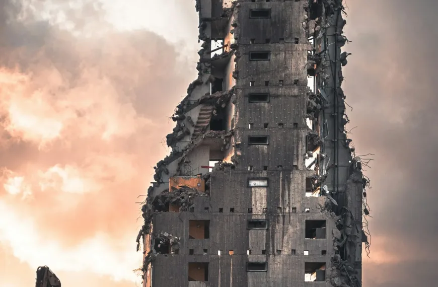 A very tall building being torn down by a machine
