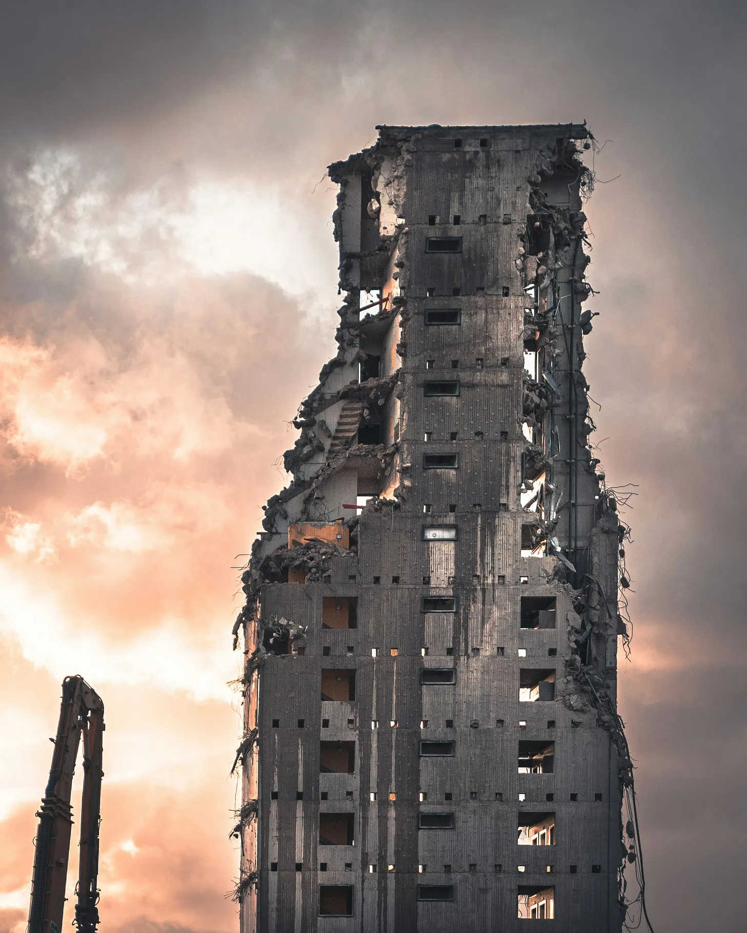 A very tall building being torn down by a machine