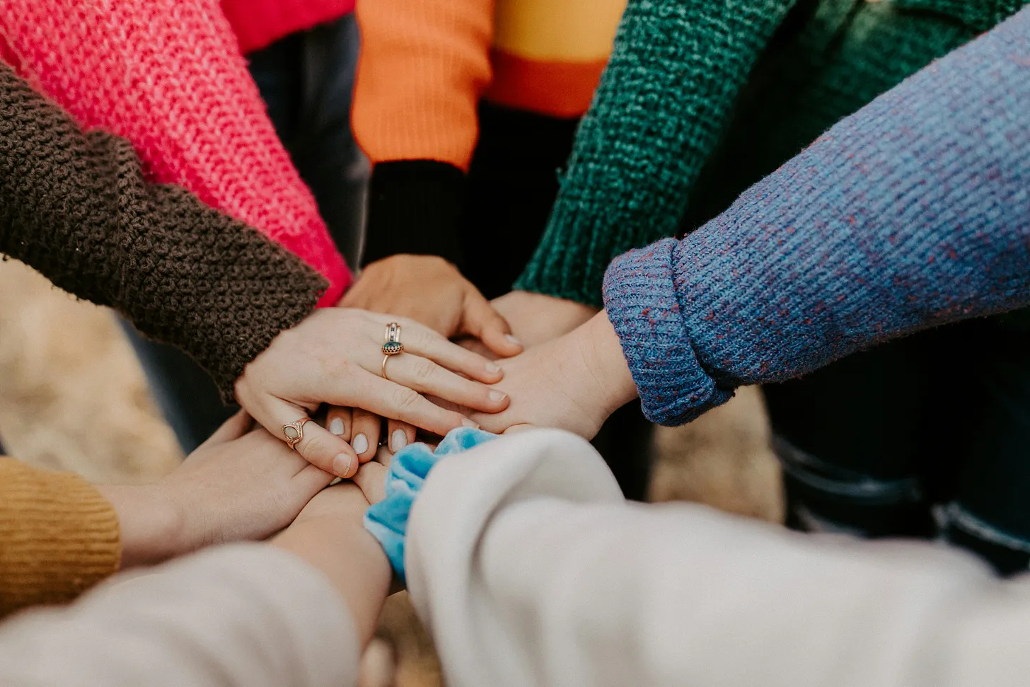 A group of people displays unity by putting each a hand on top of the others'