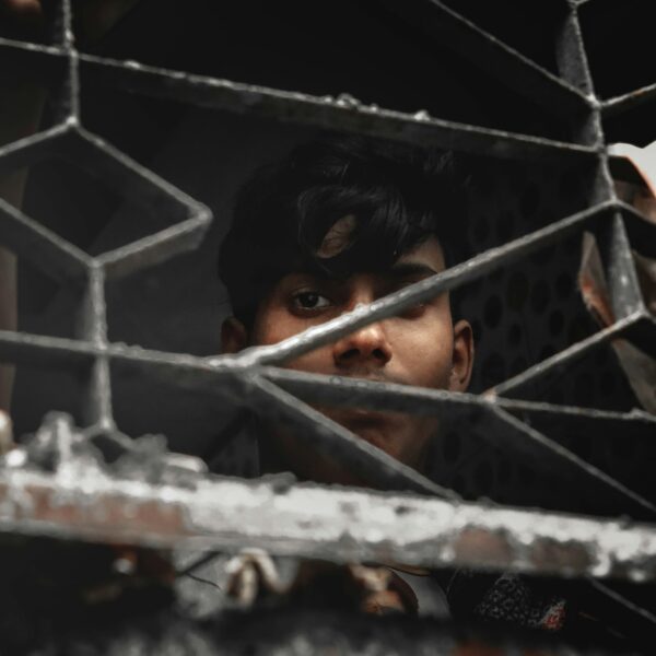 Boy standing behind metal fence