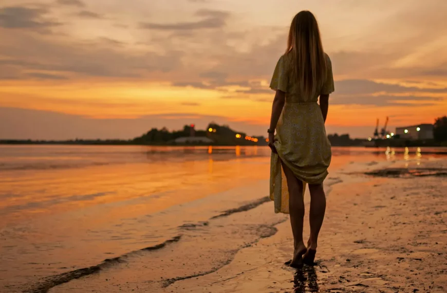 Woman standing on the beach, watching the sunset