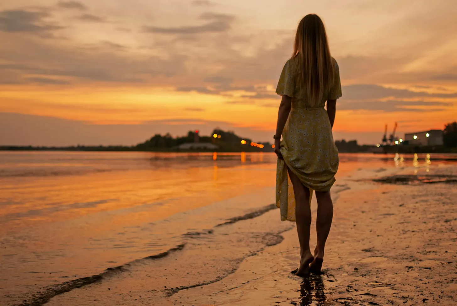 Woman standing on the beach, watching the sunset