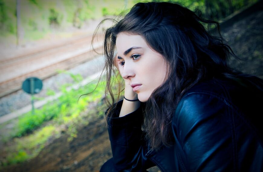 Woman looking thoughtful or sad, with a railway in the background