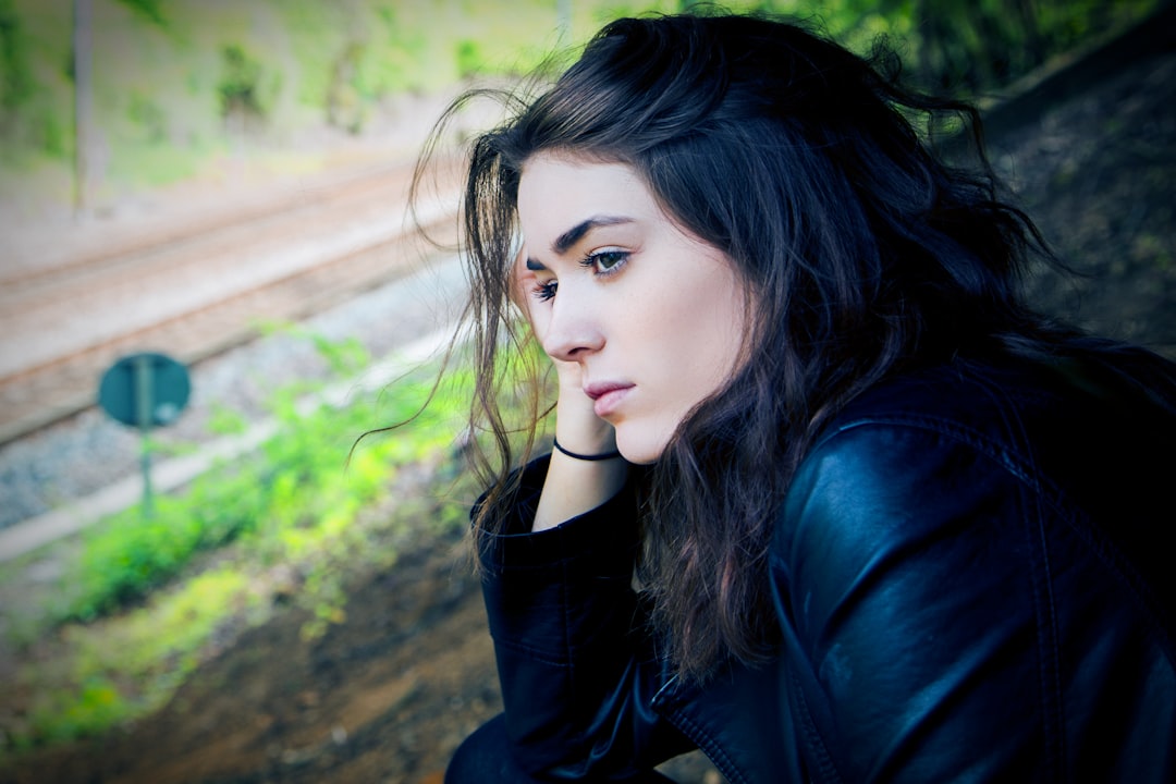 Woman looking thoughtful or sad, with a railway in the background