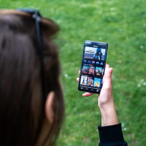 A man is looking at a smartphone, while standing on the grass