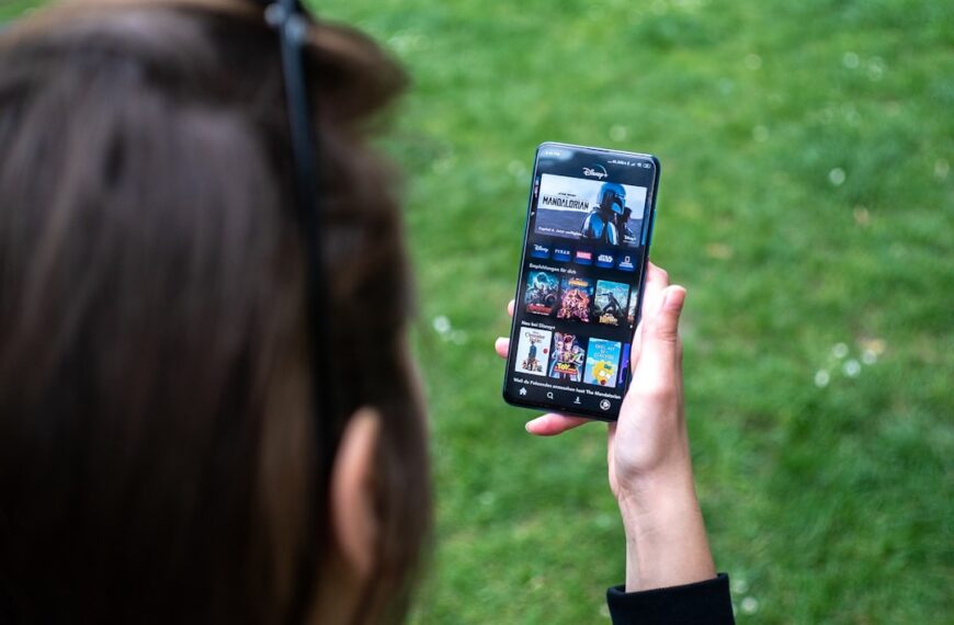 A man is looking at a smartphone, while standing on the grass