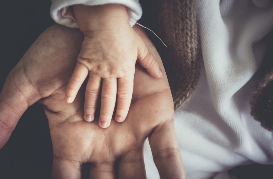 A baby hand on top of an adult's hand